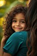 © felix_brönnimann - Child smiling while being held by a woman outdoors, showcasing warmth and connection in a joyful moment between family or friends. Bonding and affection captured.