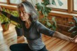 © axel - In a sunlit studio with wooden floors, a woman over 40 of Asian descent performs yoga poses, embodying mindfulness and commitment to fitness surrounded by greenery