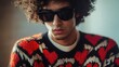 © NeuralNiche - Stylish man with curly hair and sunglasses sporting a vibrant heart-patterned cardigan in a trendy pose indoors