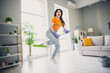 © deagreez - Young woman enjoying a joyful moment of cleaning in a vibrant living room space
