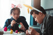 © DJ Creative Studio - Asian Teenager Wearing Bunny Headband Painting Easter Eggs at Home for Easter Festival Decoration.