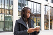 © ADDICTIVE STOCK - African American businesswoman checking smartphone outdoors
