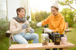 © tonefotografia - Enjoying Warm Drinks and Conversation in a Sunny Outdoor Garden During Autumn Afternoon