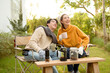 © tonefotografia - Enjoying Warm Drinks and Conversation in a Sunny Outdoor Garden During Autumn Afternoon