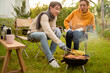 © tonefotografia - Couple Enjoys Grilling Outdoors in a Cozy Garden Setting During a Sunny Afternoon