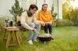 © tonefotografia - Couple Enjoys Grilling Outdoors in a Cozy Garden Setting During a Sunny Afternoon