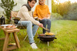 © tonefotografia - Couple Enjoys Grilling Outdoors in a Cozy Garden Setting During a Sunny Afternoon