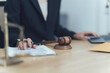 © Kritdanai - The Scales of Justice:  A close-up view of a lawyer's hands reviewing a document with a gavel and scale of justice in the foreground.