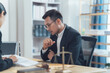 © Kritdanai - Legal Consultation: A serious and focused lawyer discusses legal documents with a client in a professional office setting.  The scene is illuminated with natural light.