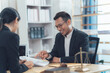 © Kritdanai - Legal Consultation:Positive and productive meeting between a lawyer and client, reviewing documents and discussing legal matters in a modern, well-lit office.
