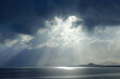 © Mayatnikstudio - Sunbeams Through Dark Clouds Over a Serene Sea Horizon