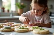© Svetlana Lavereva - young girl decorating cookies in kitchen with colorful icing - concept of baking fun, creative dessert, joyful culinary experience