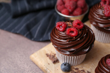 Canvas Print - Tasty cupcakes with chocolate cream and berries on brown table, closeup. Space for text