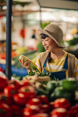 Asian female market customer holding celery and corn choosing fresh vegetables