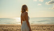 © Evgenii Starkov - Woman in a flowing white dress walking along a serene beach during golden hour, facing the calm sea.