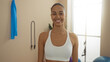 © Krakenimages.com - Woman smiling in a gym wearing a white sports bra with exercise equipment in the background