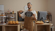 © Krakenimages.com - Young man pointing to open sign in bakery with pastries displayed and clock on the wall