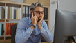 © Krakenimages.com - Handsome young arab man with a beard talking on the phone in an office setting with shelves full of books and files in the background