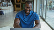 © Krakenimages.com - Handsome young man smiling while working on a laptop in an office room