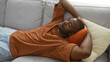 © Krakenimages.com - Handsome young african american man relaxing on a couch in a cozy living room, enjoying a peaceful moment indoors at home