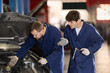 © JackF - Experienced mechanic helps a young mechanic with car repairs. Car service specialists repair the car, check the oil and engine