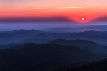 Poster - Vibrant Sunset Paints the Sky Over Silhouetted Mountain Ranges at Dusk