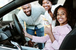 © Prostock-studio - Cute black girl sitting inside new car, showing thumb up gesture, recommending auto dealership with her parents. Successful test drive, best automobile showroom store concept