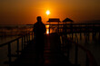 © Janwar - Silhouette of a man sitting at the gate enjoying the beautiful sunset on the beach