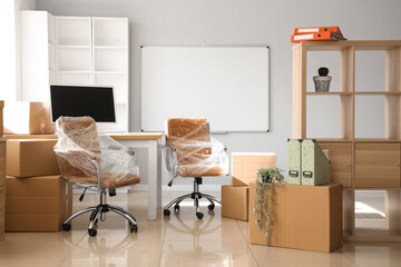 Wall Mural - Interior of office with chairs wrapped in stretch film and cardboard boxes on moving day