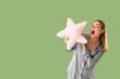 © Pixel-Shot - Shocked young woman with soft pillow in shape of star on green background