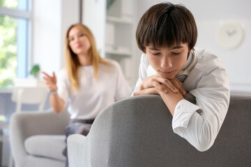 Wall Mural - Sad teenage boy sitting at psychologist's office