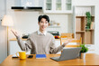 © Nuttapong punna - Young man using laptop while sitting at home. Young woman sitting in kitchen and working
