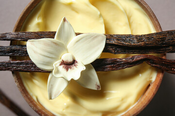 Wall Mural - Bowl of tasty pudding, vanilla sticks and flower on color background, closeup