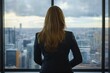 © Firn/imageBROKER - Back view of business woman looking out of window in office. Generative Ai, AI generated