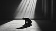 © musa - Man kneeling in sunlit hall, monochrome.