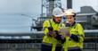 © Dee karen - Male and female industrial engineers wearing hard hats talk to collaborate on new project. Team of engineers inspecting gas separation plant using tablets.
