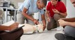 © CineLens24/peopleimages.com - People, mannequin and training in office for first aid, CPR workshop or choking prevention lesson. Team, emergency practice or dummy in agency for open airways procedure, notes or employee engagement