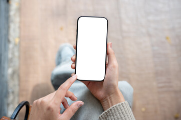 top view of a woman uses her phone while sitting indoors. the smartphone with a white screen mockup