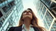 © Keopaserth - Modern businesswoman looking up at skyscrapers in cityscape, showcasing ambition and determination. sunlight reflects off glass buildings, creating vibrant atmosphere