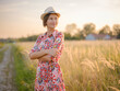 © YURII Seleznov - Young woman walking through picturesque European field in late summer. Golden sunlight, lush greenery, and serene rural atmosphere create peaceful countryside scene.