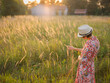 © YURII Seleznov - Young woman walking through picturesque European field in late summer. Golden sunlight, lush greenery, and serene rural atmosphere create peaceful countryside scene.