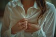 © Carlos Sanchez Pereyra/imageBROKER - A close-up of a woman buttoning her white shirt, bathed in warm light, AI generated