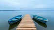 © sunchai - Serene view of two blue boats docked at a wooden pier, set against calm waters and a cloudy sky, perfect for relaxation and escape.