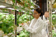 © Seventyfour - Asian scientist examining plants in controlled indoor environment wearing protective glasses and lab coat inspecting plant growth and health in research facility