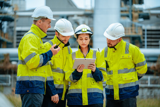 construction team discusses project details at industrial site during daytime with safety gear and t