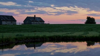 Fototapete - Beautiful rural landscape at sunset reflecting in the calm water with houses and fields near a serene pond