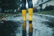 © Alexei - A person in yellow rain boots is standing in a puddle