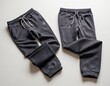 © Viktor Petrushenko - Two pairs of stylish dark gray sweatpants laid out flat with adjustable drawstrings.