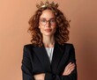 © ECLIVN - A confident young woman with curly hair, wearing glasses and a crown, poses in a stylish black blazer against a warm background. Crowned for Success , Leadership and Ambition
