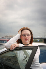 Wall Mural - A young model in her 20s in light-colored jeans walks around the city. Mild spring weather. Local tourism.